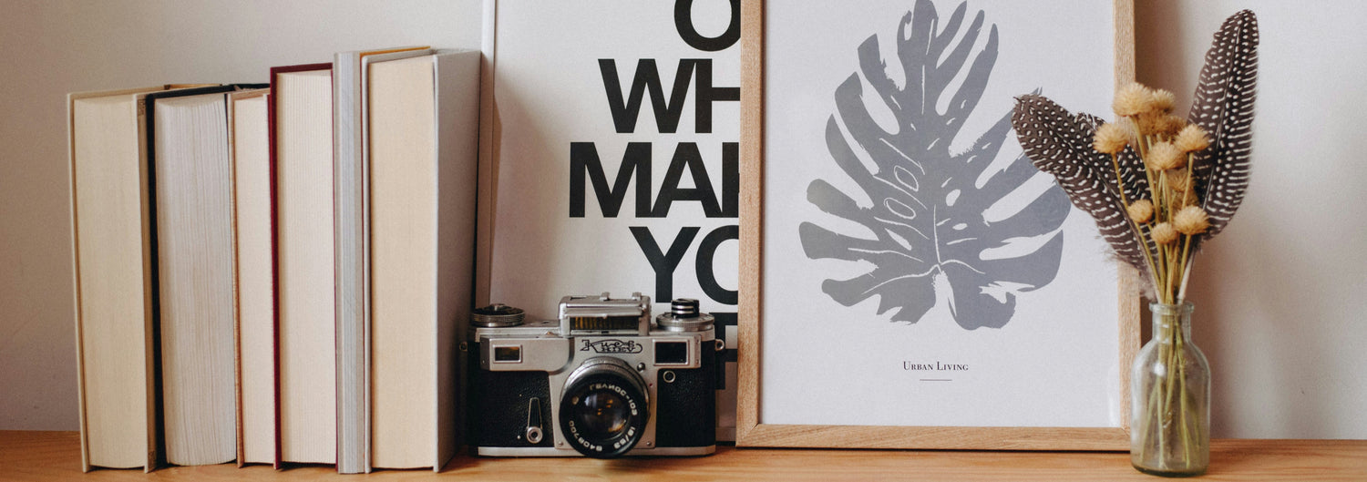 Composizione home decor lifestyle con quadri moderni, libri e macchina fotografica vintage su mensola in legno di Tutto Casa Igiene & Homedecor
