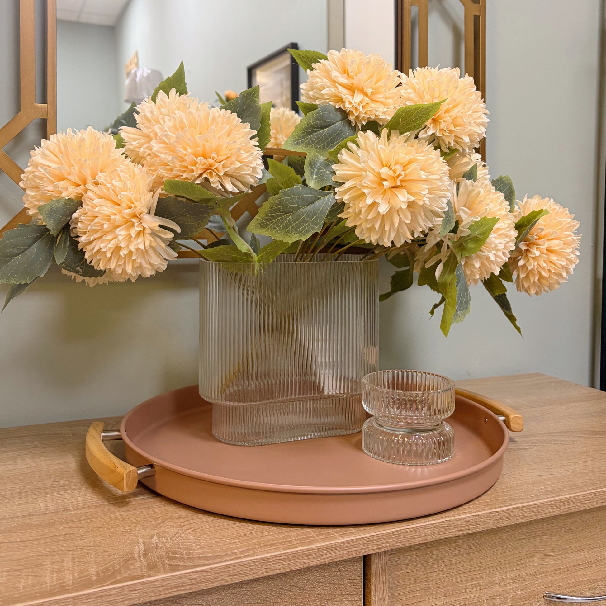 Il portacandele in vetro trasparente design plissè a coste sul vassoio moderno rosa antico con i manici di legno e vaso plissè con le dalie finte