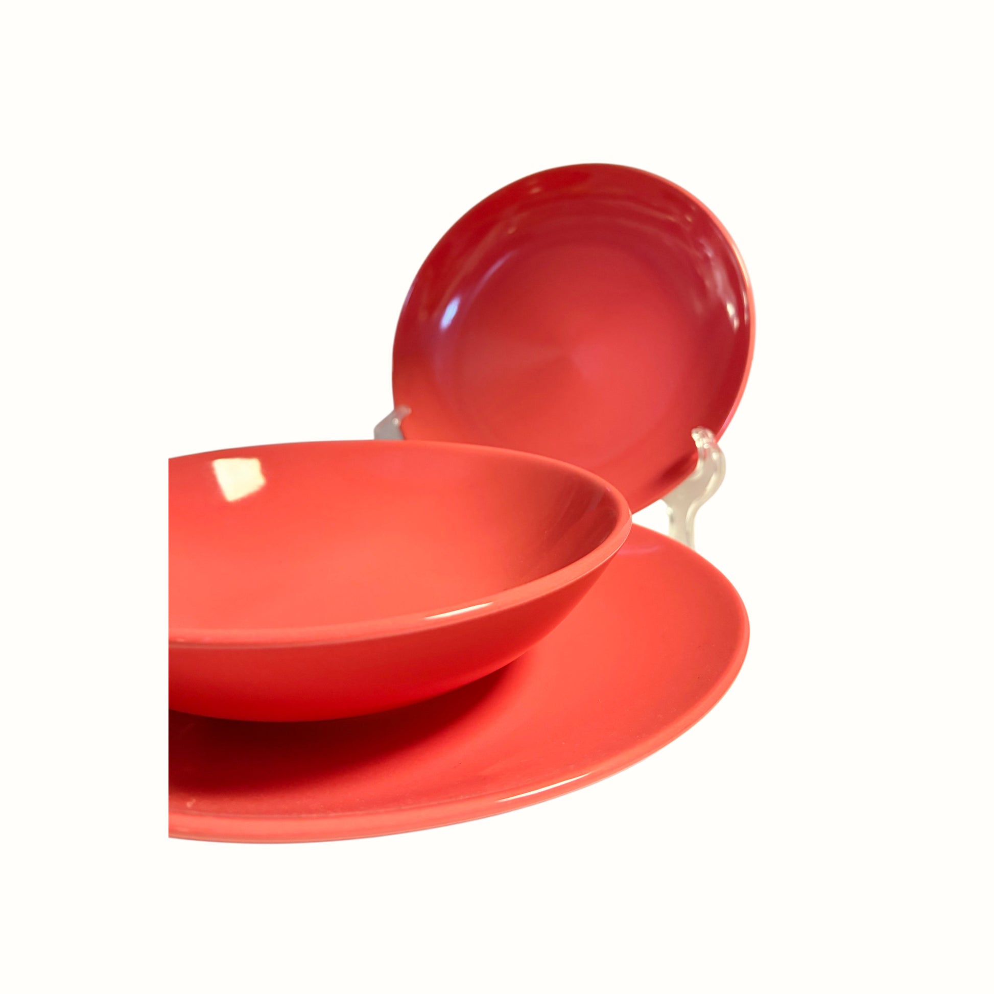 Dettaglio ravvicinato della finitura lucida e del bordo del set di piatti in ceramica color corallo.